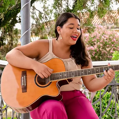 Evelyn Cardoso tocando violão e cantando na varanda