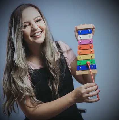 Isabela Oliveira, fundadora do Musicalisa, sorrindo com um xilofone colorido nas mãos