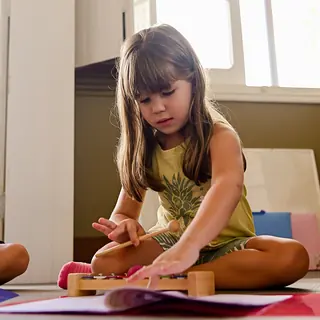 Menina toca xilofone sentada no chão