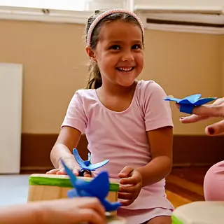 Menina sorridente tocando tambor na aula
