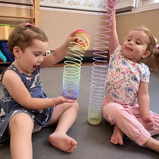 Duas crianças pequenas brincando com molas coloridas